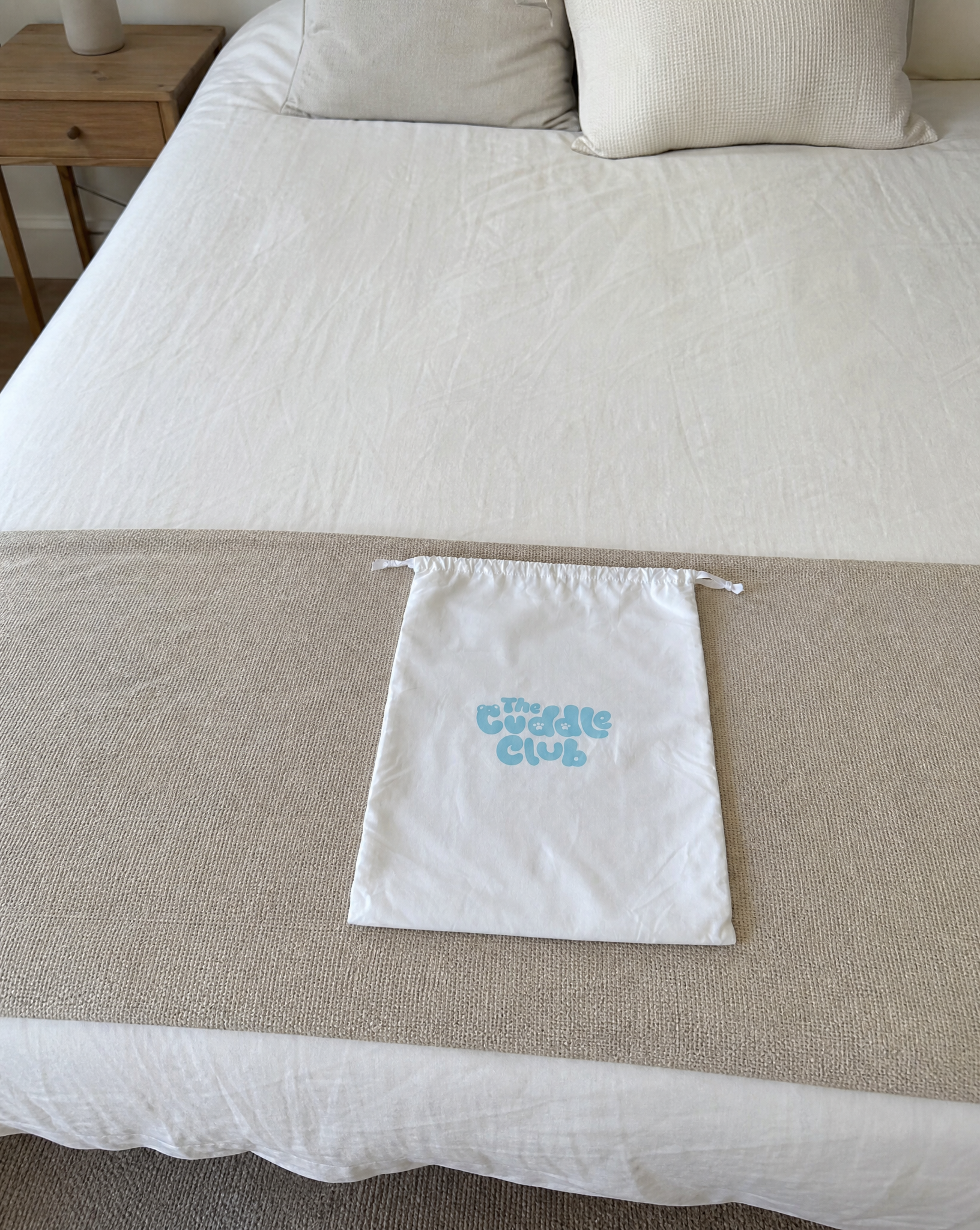 The Cuddle Club signature dust bag on a bed